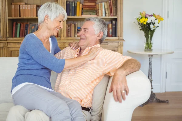 Sorridente donna anziana seduta in grembo di uomo in soggiorno — Foto Stock