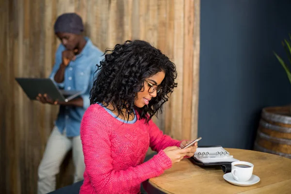 Γυναίκα που χρησιμοποιούν κινητό τηλέφωνο πίνοντας καφέ σε καφετέρια — Φωτογραφία Αρχείου