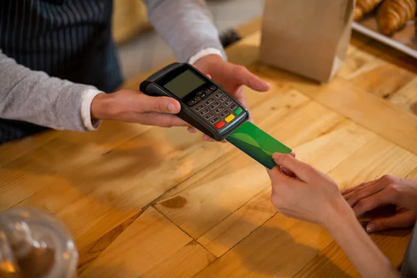 Cliente fazendo o pagamento através do cartão de crédito no balcão — Fotografia de Stock