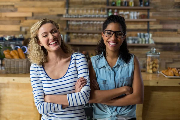 Retrato de amigas de pie con los brazos cruzados cerca del mostrador — Foto de Stock