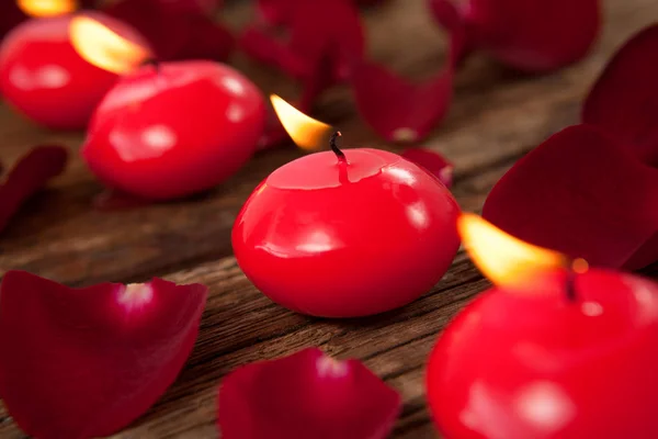 Velas de cera roja rodeadas de pétalos de rosa — Foto de Stock