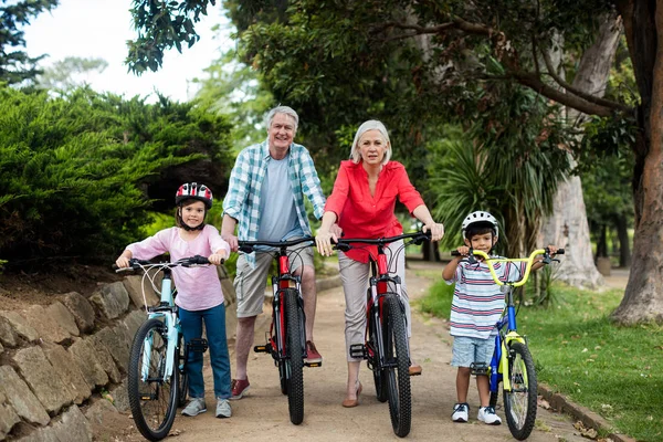 Retrato de família multi-geração de pé com bicicleta no parque — Fotografia de Stock