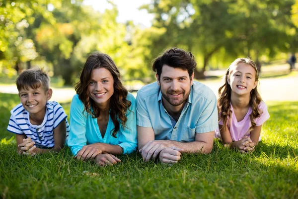 Porträtt av lycklig familj liggande på gräset i parken — Stockfoto