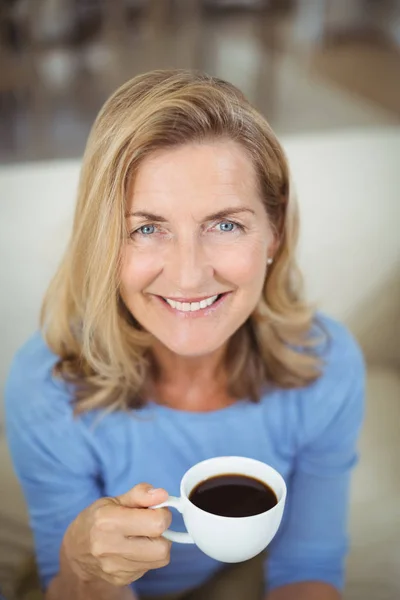 Mujer mayor sonriente tomando una taza de café en el salón — Foto de Stock