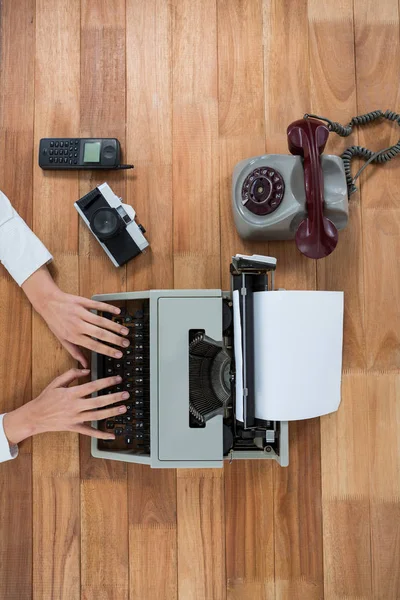 Businesswoman typing on typewriter with vintage camera, telephone and mobile phone — Stock Photo, Image