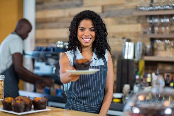 Portret uśmiechający się kelnerka trzymając płytkę z cupcake — Zdjęcie stockowe