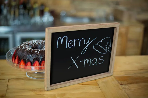 Merry x mas sign board dengan kue di counter — Stok Foto