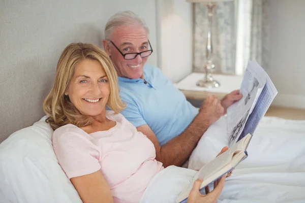 Casal sênior na cama ler jornal e livro — Fotografia de Stock