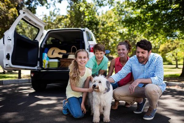 Família feliz sentada no parque com seu cão — Fotografia de Stock