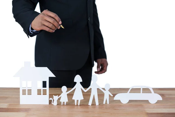 Mid section of businessman with paper cut out family, house and car at desk — Stock Photo, Image