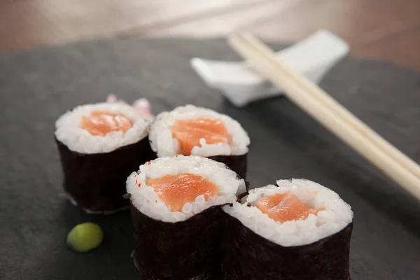 Quatre sushis nigiri servis avec des baguettes sur de l'ardoise de pierre noire — Photo