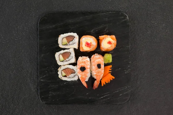 Uramaki och nigiri sushi serveras i svart sten skiffer — Stockfoto