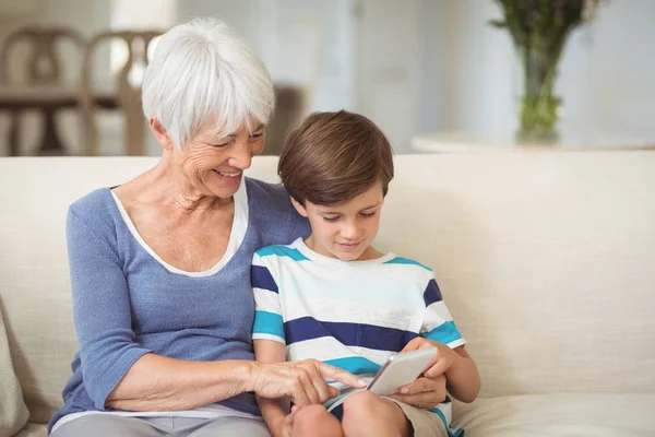 Vnukem a babičkou pomocí mobilního telefonu v obývacím pokoji — Stock fotografie