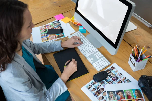Designer gráfico feminino usando tablet gráficos na mesa — Fotografia de Stock