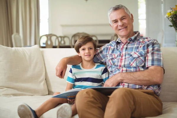 Retrato del abuelo con su nieto sosteniendo el libro en el sofá — Foto de Stock