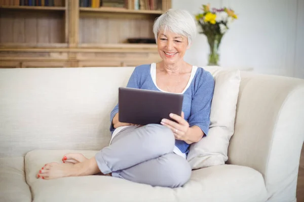 Femme âgée utilisant une tablette numérique dans le salon — Photo