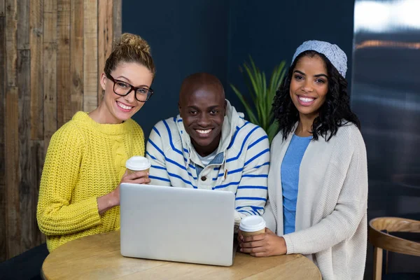 Amigos felizes usando laptop enquanto toma café no café — Fotografia de Stock