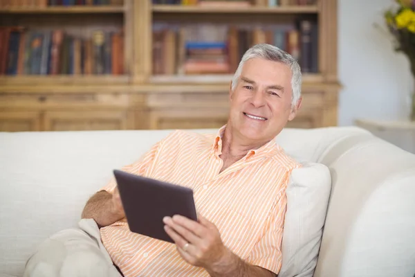 Lachende senior man met digitale tablet in woonkamer — Stockfoto