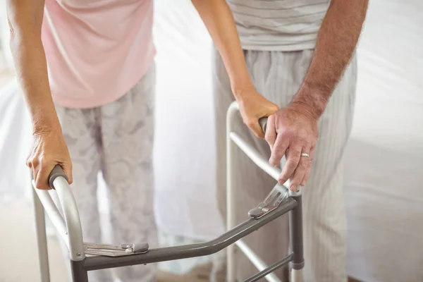 Mid section of senior man helping woman to walk with walker — Stock Photo, Image