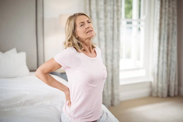 Senior woman having back pain in bedroom — Stock Photo, Image