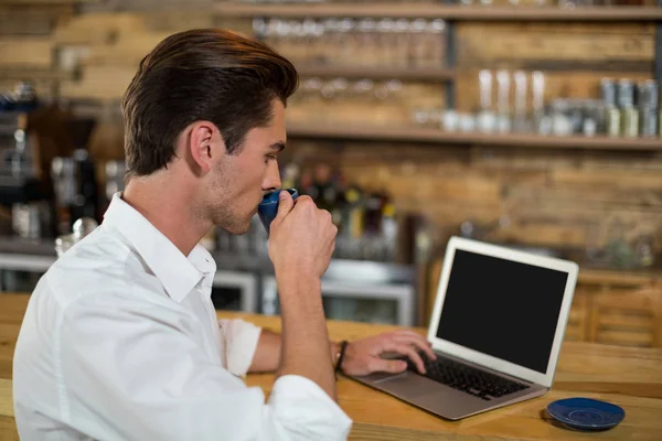 Ο άνθρωπος που έχει καφέ ενώ χρησιμοποιείτε φορητό υπολογιστή — Φωτογραφία Αρχείου