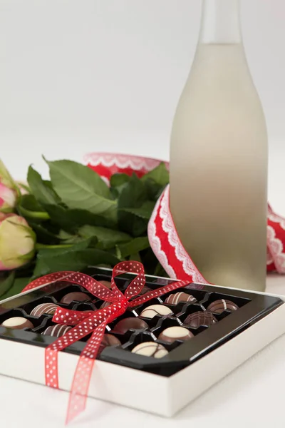 Ramo de rosas, botella de champán y caja de chocolate surtido — Foto de Stock