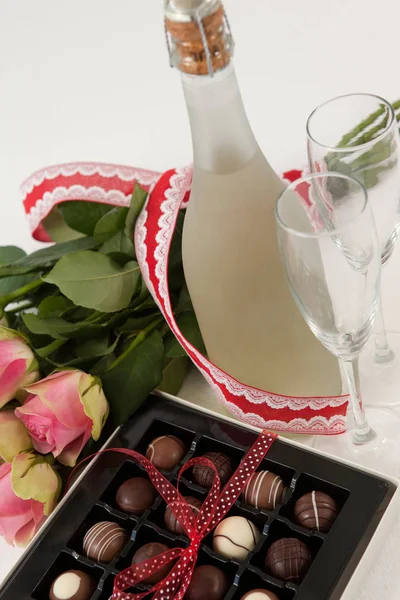 Ramo de rosas, botella de champán, copas de vino y una variedad de cajas de chocolate — Foto de Stock