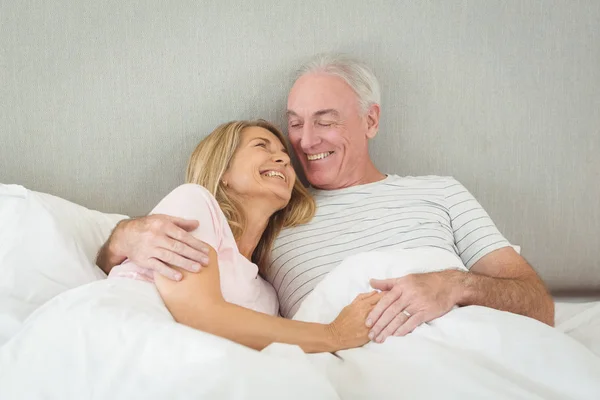 Casal sênior abraçando na cama — Fotografia de Stock