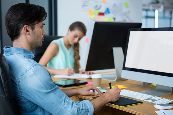 Männlicher Grafikdesigner mit Grafik-Tablet am Schreibtisch — Stockfoto