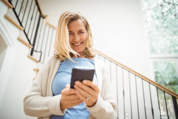 Mosolygó idősebb nő, otthoni mobiltelefon használata — Stock Fotó