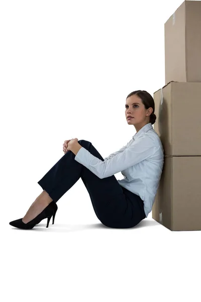 Empresária encostada em caixas de papelão contra fundo branco — Fotografia de Stock