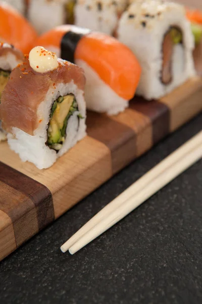 Blandade sushi set serveras med ätpinnar på träskiva — Stockfoto