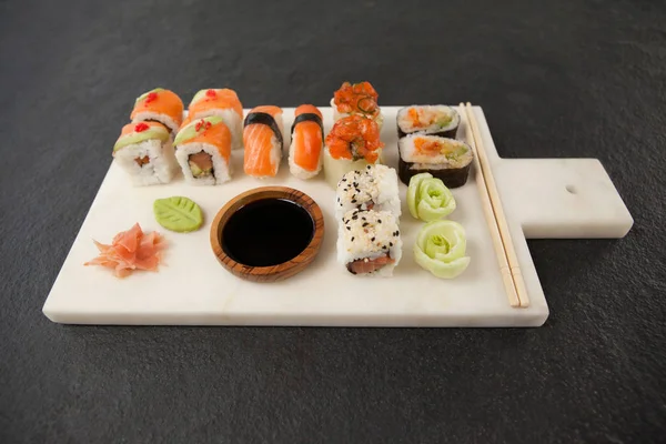 Surtido de sushi servido con salsa de soja y palillos en pizarra blanca —  Fotos de Stock