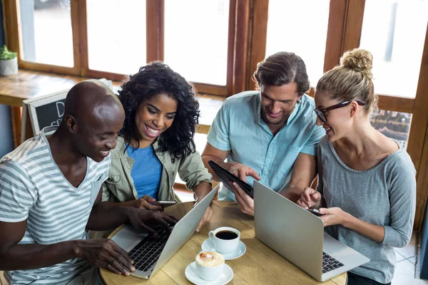 Vrienden met behulp van laptop, mobiele telefoon en digitale tablet terwijl het hebben van koffie — Stockfoto