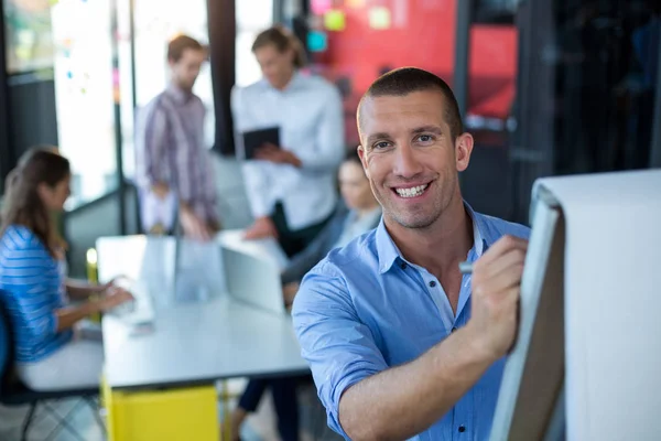 Porträt eines Geschäftsmannes, der auf Flipchart schreibt — Stockfoto