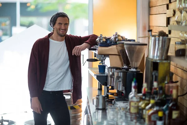 Портрет улыбающегося владельца, стоящего рядом с кофеваркой — стоковое фото