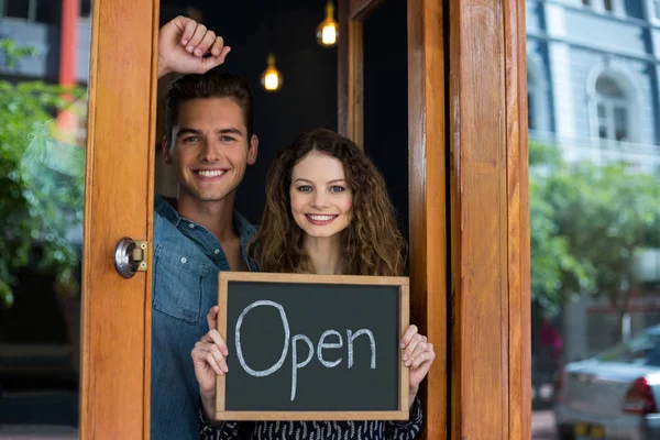 Portrait of man and woman showing chalkboard with open sign — Stock Photo, Image