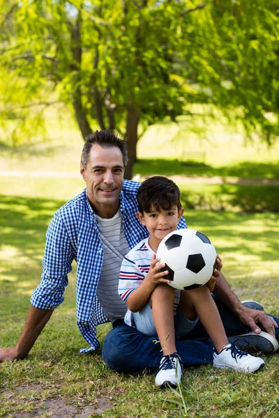 Portrait of father and son sitting in park — Stock Photo, Image