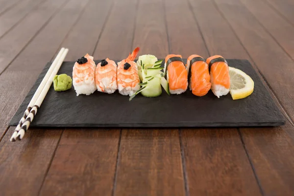 Nigiri sushi serveras med ätpinnar i svart sten skiffer — Stockfoto