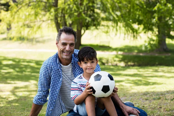 Portrait de père et fils assis dans le parc — Photo