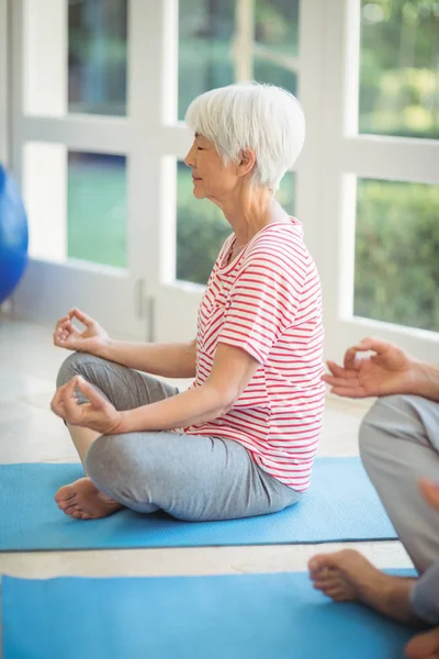 Pareja mayor realizando yoga en colchoneta de ejercicio —  Fotos de Stock