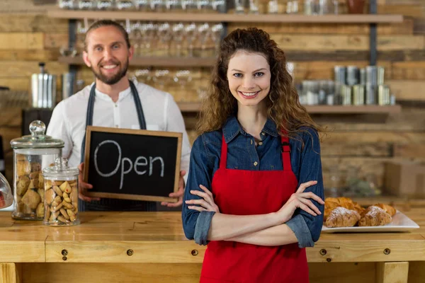 Waitress standing with arms crossed at counter in cafe — Stock Photo, Image