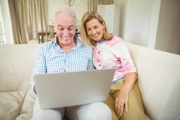 Casal sênior usando laptop na sala de estar — Fotografia de Stock