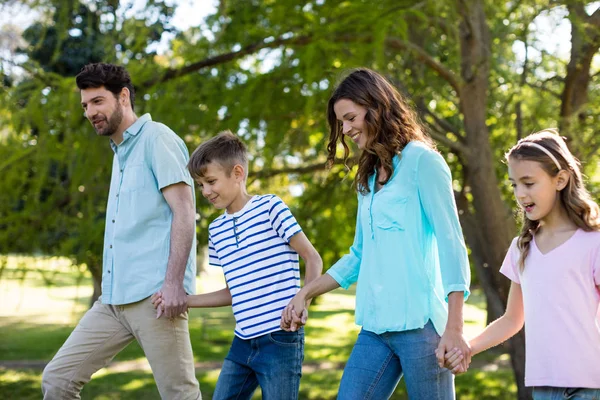 Счастливая семья, гуляющая по парку рука об руку — стоковое фото