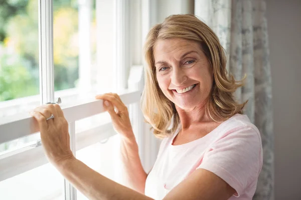 Porträt einer glücklichen Seniorin, die am Fenster steht — Stockfoto
