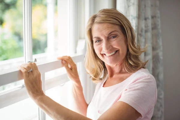 Portrait of happy senior woman standing next to window — Stock Photo, Image