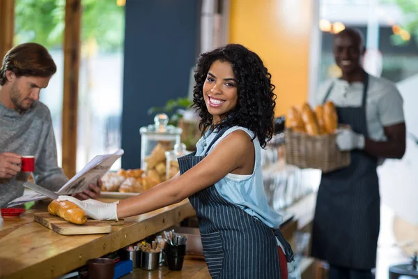 Portrait of waitress serving at counter in cafe — Stock Photo, Image