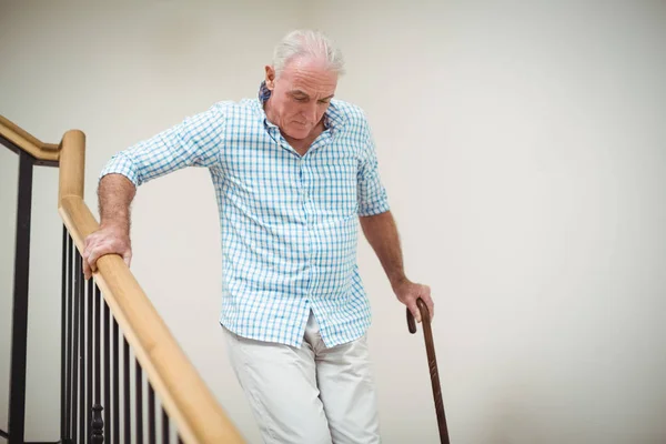 Senior man climbing downstairs with walking stick — Stock Photo, Image