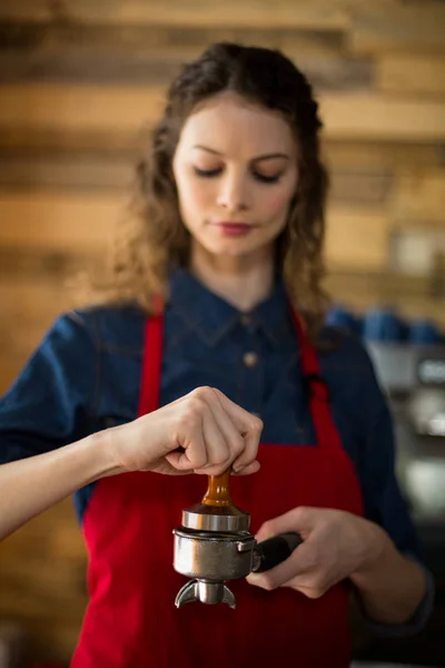 Serveuse utilisant un tampon pour presser du café moulu dans un portable — Photo