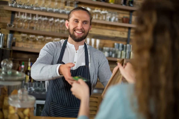 Kunden ger kreditkort till servitrisen medan de får paket på counter — Stockfoto